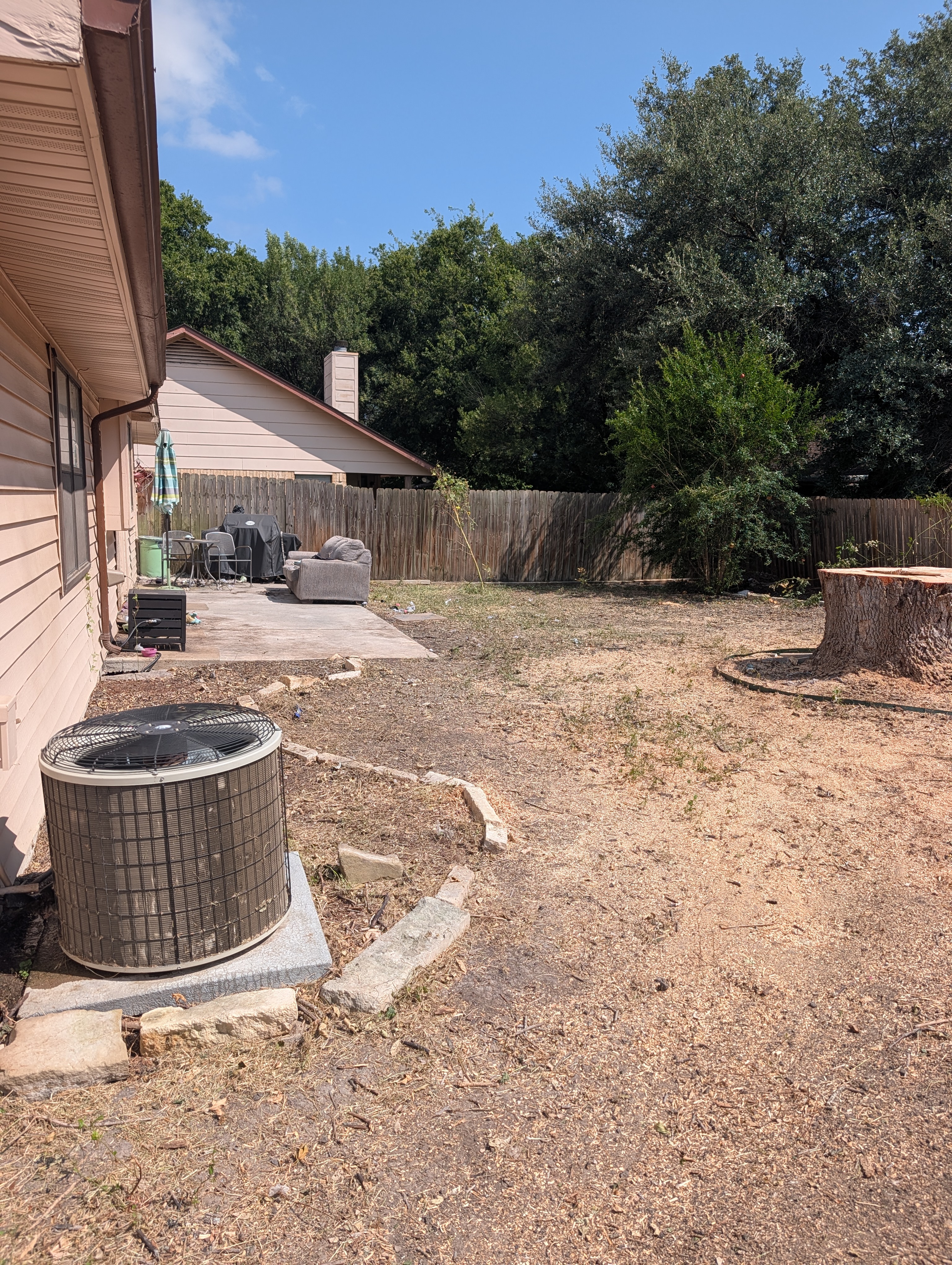 Spotless backyard post-removal, showing intact AC unit, clean stump, and fully protected home.